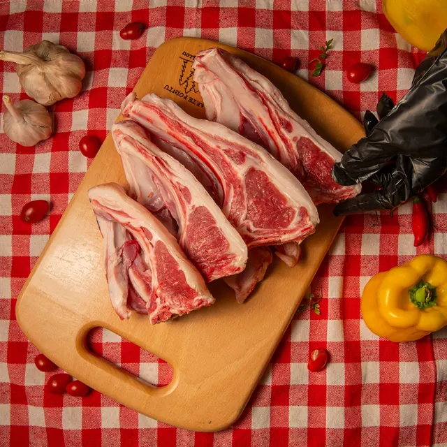 Côtes de bœuf crues sur une planche de bois, nappe à carreaux rouges