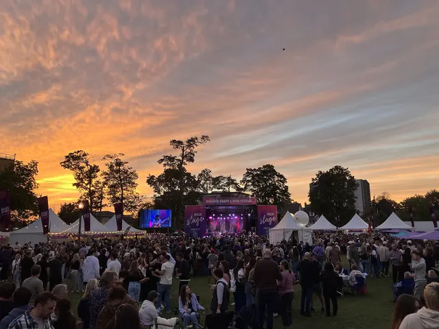 Foule devant une scène de festival en plein air au coucher du soleil