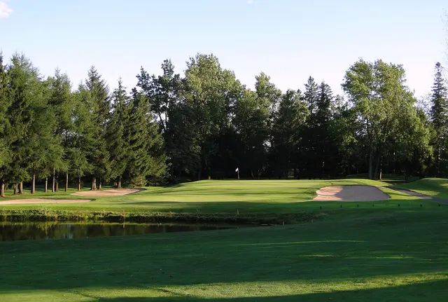 Vert et fosse de sable bordés de conifères sur un terrain de golf du Québec