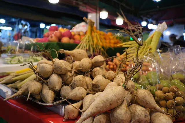 Légumes racines, maïs et fruits empilés sur l'étal d'un marché public