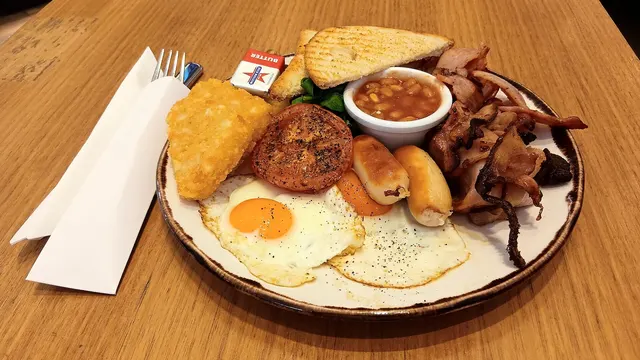 Assiette de déjeuner avec œufs miroir, bacon, fèves au lard, galette de pommes de terre et rôties