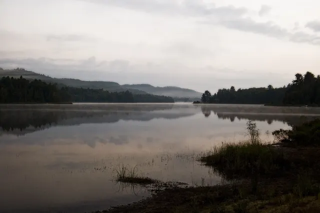 Lac entouré de forêt et de collines dans la brume du petit matin