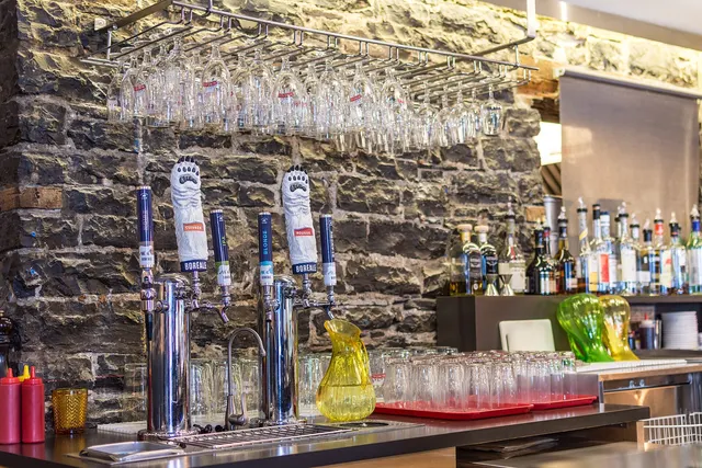 Comptoir de bar avec ses pompes à bière devant un mur de pierre, dans le Vieux-Québec
