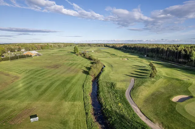 Vue aérienne d'un parcours de golf au Québec, avec un ruisseau qui serpente