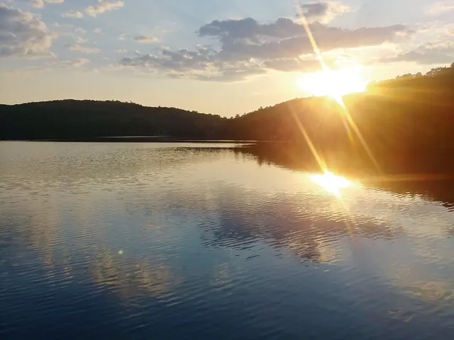 Coucher de soleil sur un lac entouré de collines boisées