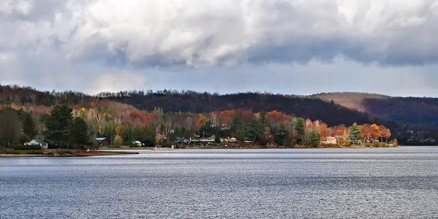 Le lac Simon en automne, avec les chalets et les collines colorées sur l'autre rive