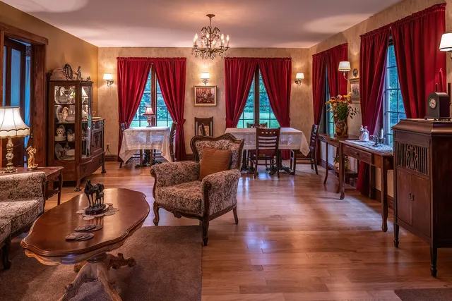 Salon d'une auberge de l'île d'Orléans avec rideaux rouges, lustre et meubles anciens
