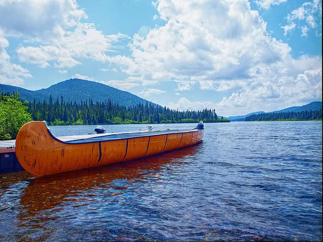 Grand canot amarré sur le lac Cascapédia, entouré de forêt et de montagnes