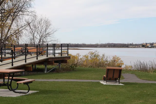 Tables à pique-nique et belvédère de bois au bord de la rivière dans un parc