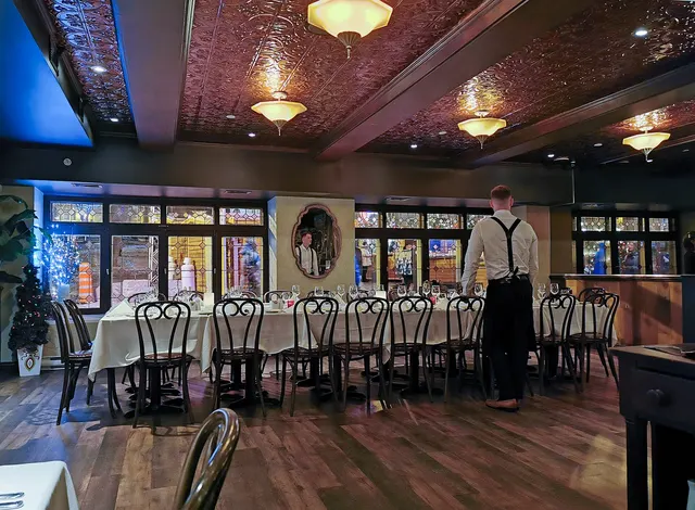 Salle à manger d'une auberge du Vieux-Québec, tables nappées de blanc et plafond en tôle ouvragée