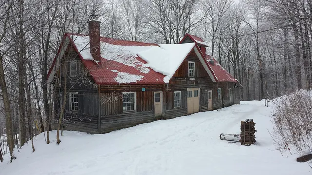 Cabane à sucre en bois rond au milieu d'une érablière enneigée, à Duchesnay