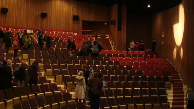 Salle de spectacle avec rangées de fauteuils rouges et murs de bois