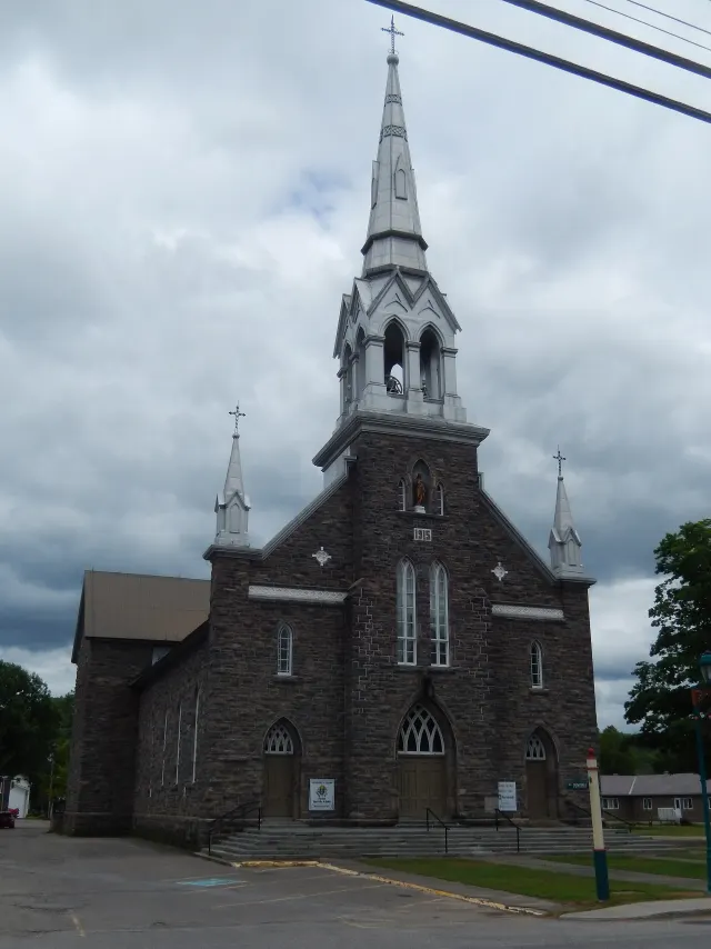 Église Saint-Félix-de-Valois en pierre avec son clocher pointu, à Chénéville