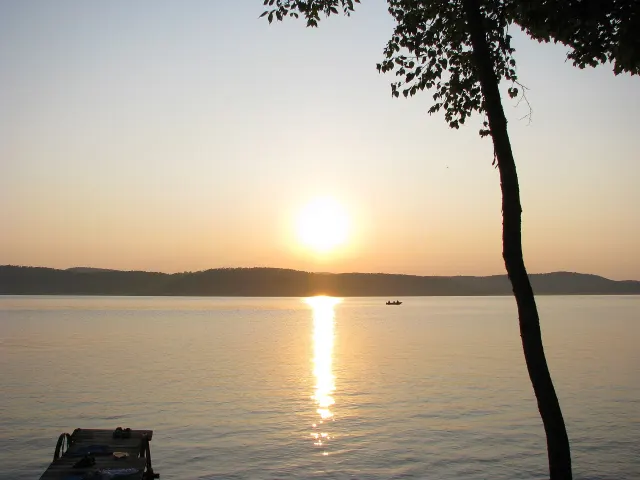 Coucher de soleil sur le lac Gagnon, avec un arbre en silhouette et une barque au loin