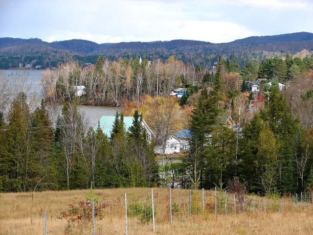Le village de Lac-des-Plages au bord du lac, avec des arbres colorés et des montagnes