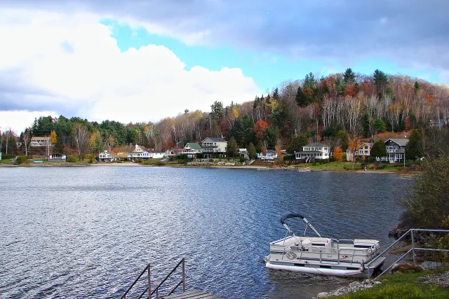 Ponton amarré devant une rive du lac Simon bordée de maisons et d'arbres d'automne