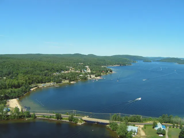 Vue aérienne du lac Simon avec sa plage, ses rives boisées et un bateau