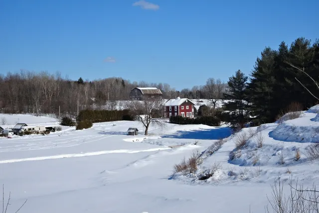Champs enneigés, ferme rouge et grange sous un ciel bleu à Lochaber-Partie-Ouest