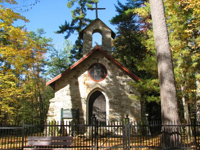 Petite chapelle funéraire en pierre de la famille Papineau entourée d'arbres d'automne