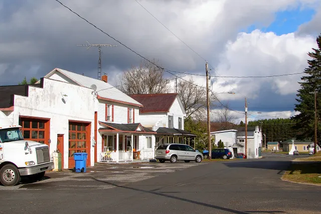 Rue du village de Notre-Dame-de-la-Paix avec un ancien garage et des maisons