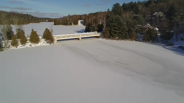 Pont au-dessus du lac Saint-Émile gelé, forêt de conifères en décembre