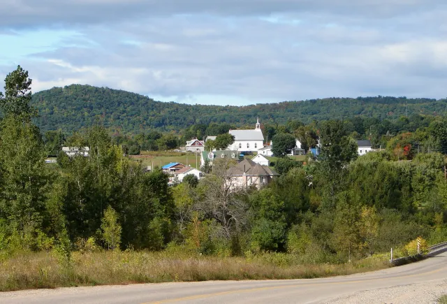 Le village de Saint-Sixte et son église blanche au pied des collines boisées