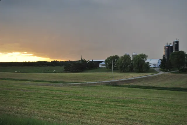 Champs et ferme avec silos sous un ciel de fin de journée à Thurso